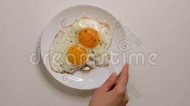 盘子里有两个煎蛋。 把盘子和煎蛋放在木桌上。 用煎蛋把白<strong>瓷盘</strong>合上